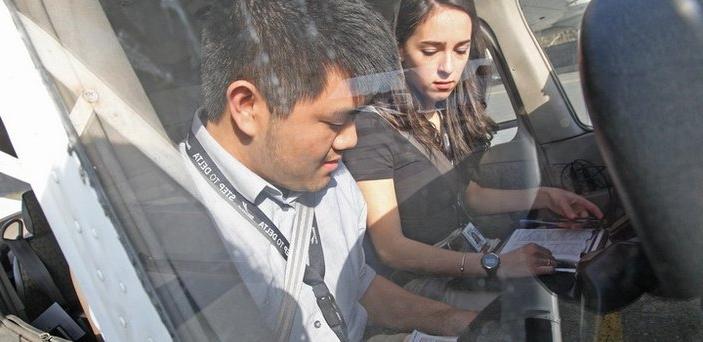 Two people in the cockpit of a plane reviewing paperwork. One person is wearing a lanyard that says Step to Delta.